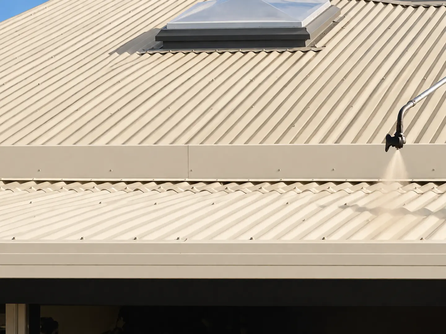 Cream coating being spray applied to a prepared metal roof in Latrobe Tasmania