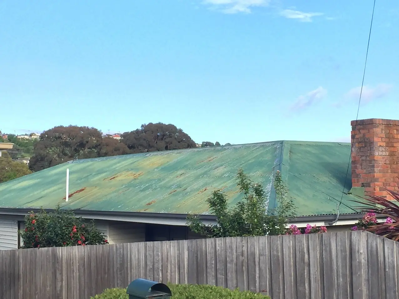 Weathered green metal roof with visible surface rust before preparation in Launceston